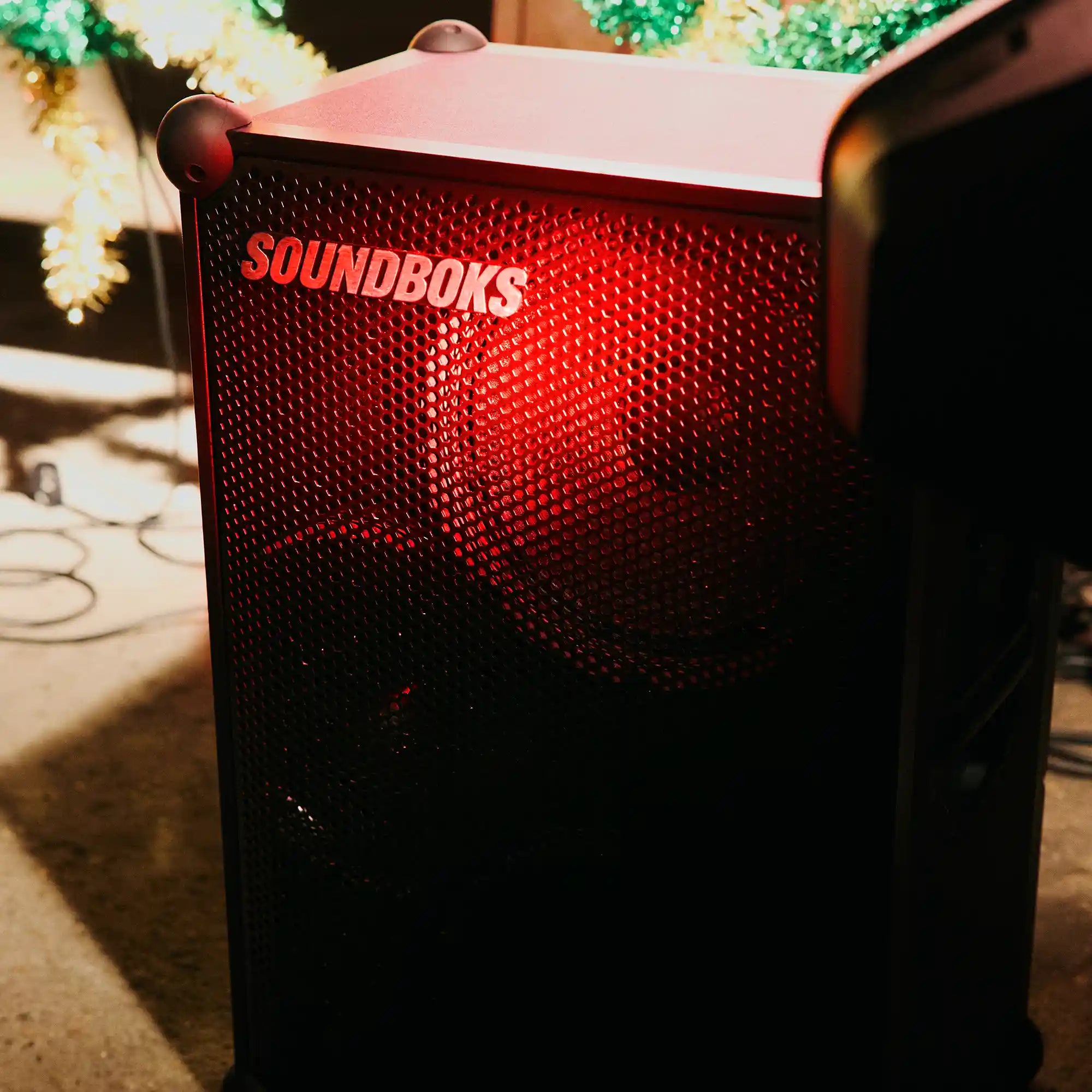 The Soundboks 4 on floor in red light#grillfarbe_metallgrau,en:grill-color_metallic-gray